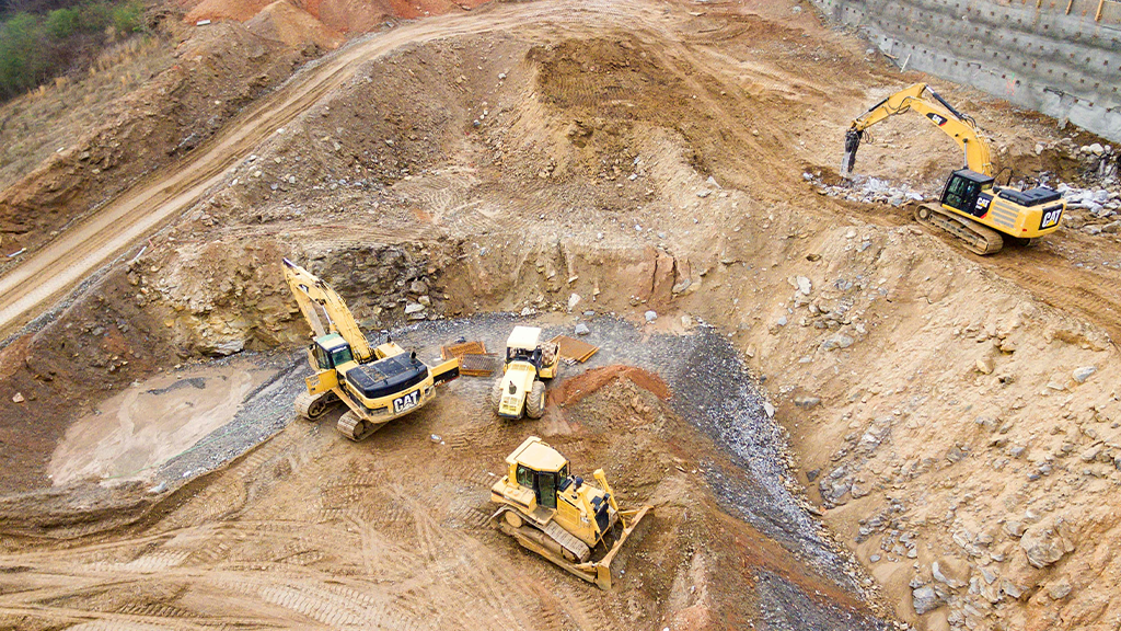 An aerial view of an above ground mining pit with several heavy machines An aerial view of an above ground mining pit with several heavy machines