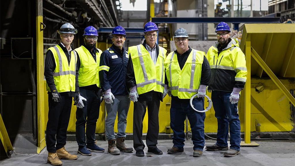 Several men wearing full PPE and high-visibility jackets pose for a photo at a Thermomechanical Treatment Facility Several men wearing full PPE and high-visibility jackets pose for a photo at a Thermomechanical Treatment Facility