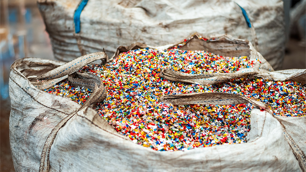 A bag filled with crushed pieces of post-consumer plastics A bag filled with crushed pieces of post-consumer plastics