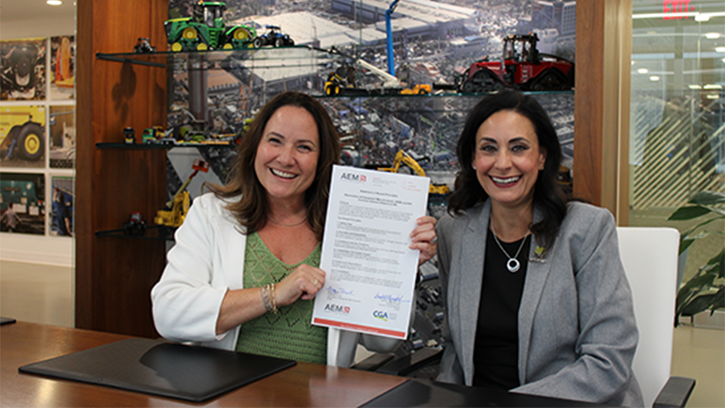 Two women sit at a desk with a signed piece of paper Two women sit at a desk with a signed piece of paper