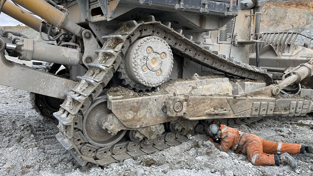 A man works on the track of a large off-the-road vehicle A man works on the track of a large off-the-road vehicle