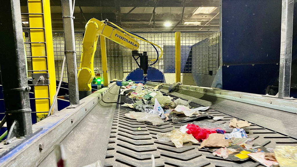 A robotic arm sorts through recyclables on a conveyor belt