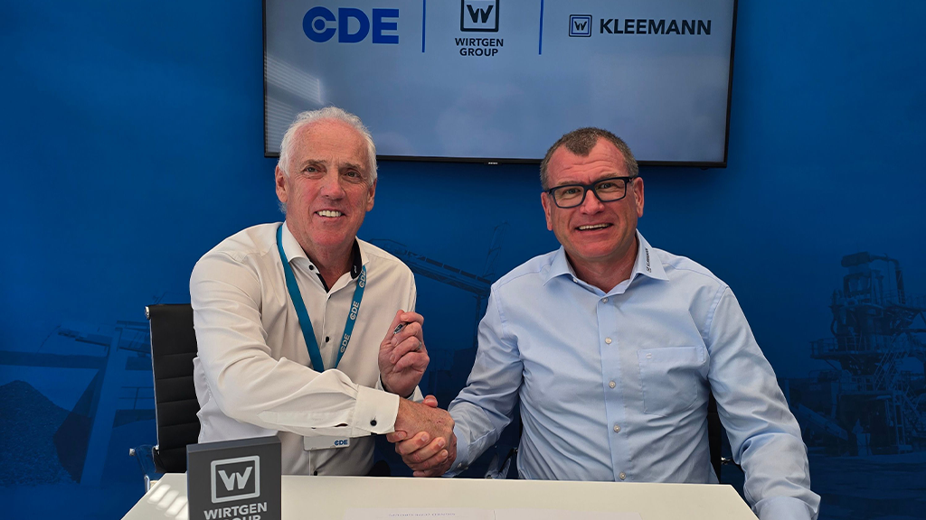 Two men sitting at a table while shaking hands
