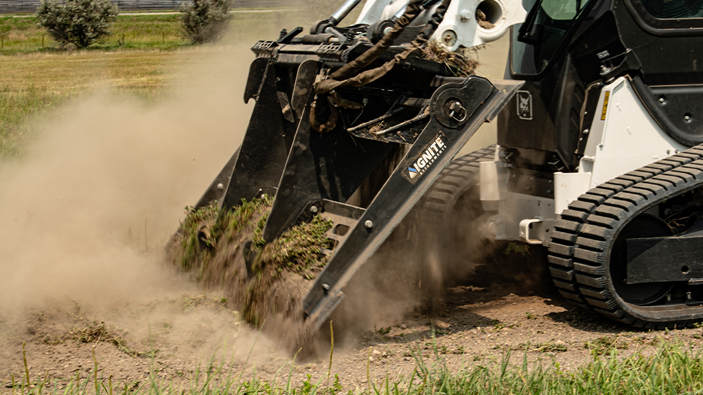 A land leveller breaking apart grass