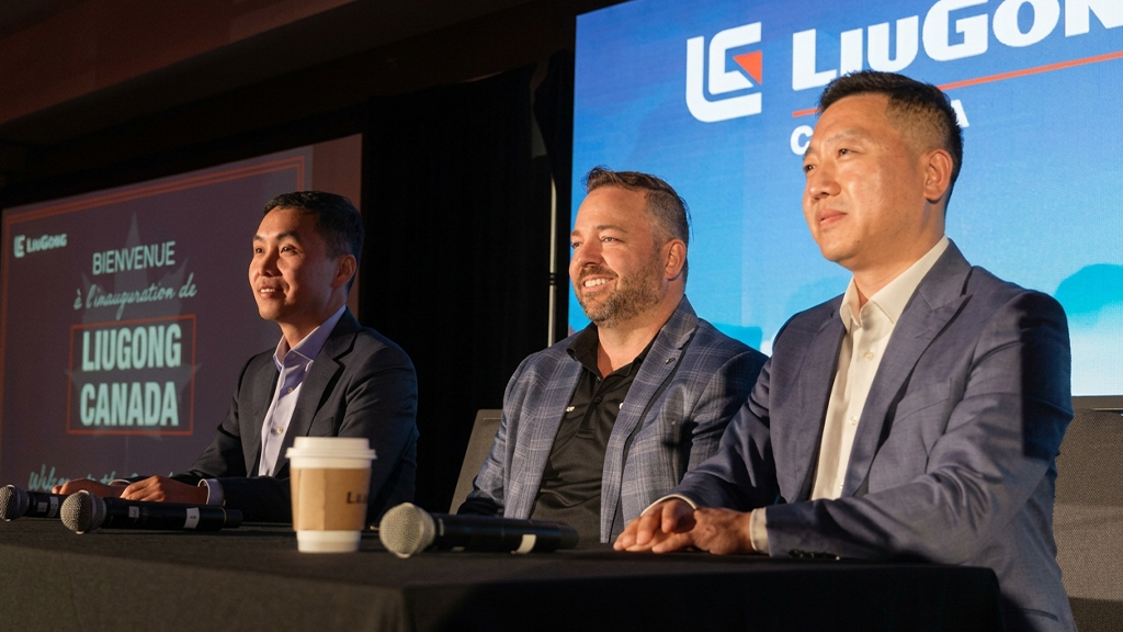 Three men sit at a table in front of the LiuGong company logo Three men sit at a table in front of the LiuGong company logo