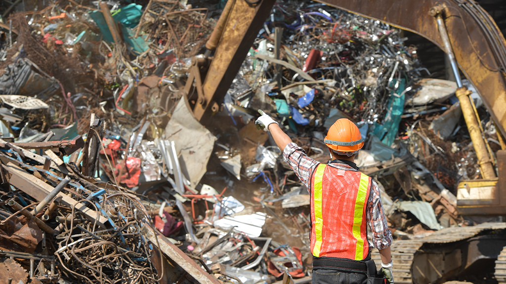 A man wearing PPE stands next to a large mixed recyclables processing pile A man wearing PPE stands next to a large mixed recyclables processing pile