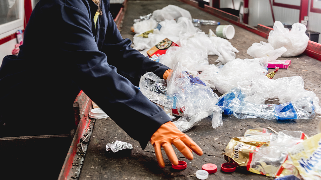A person sorts through recyclables on a moving conveyor belt