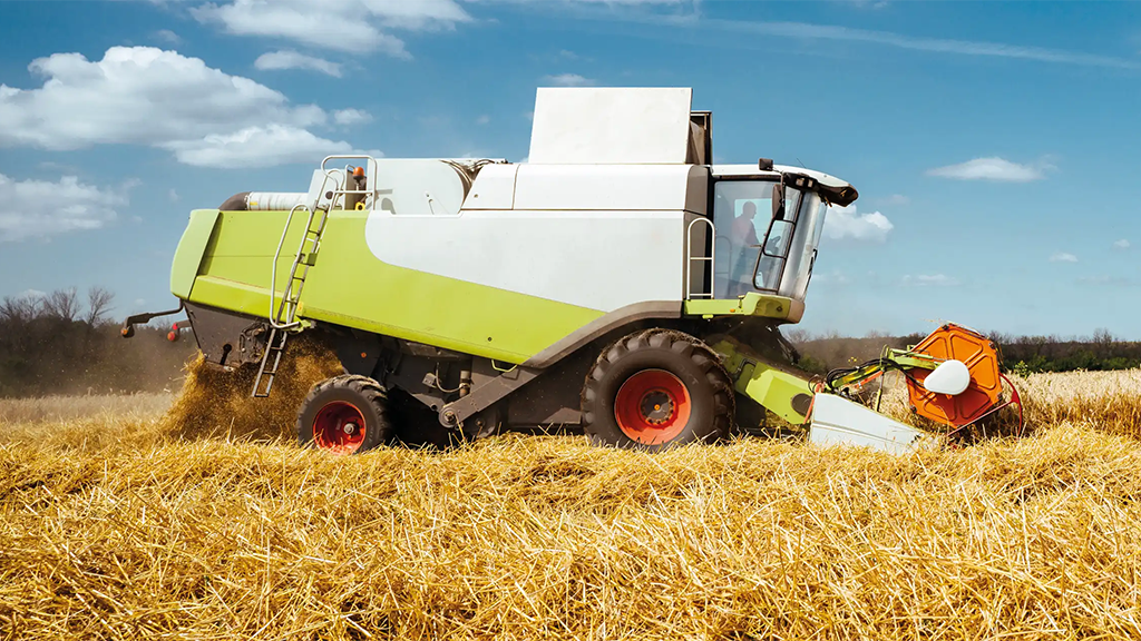 A combine harvester moves through a wheat field.