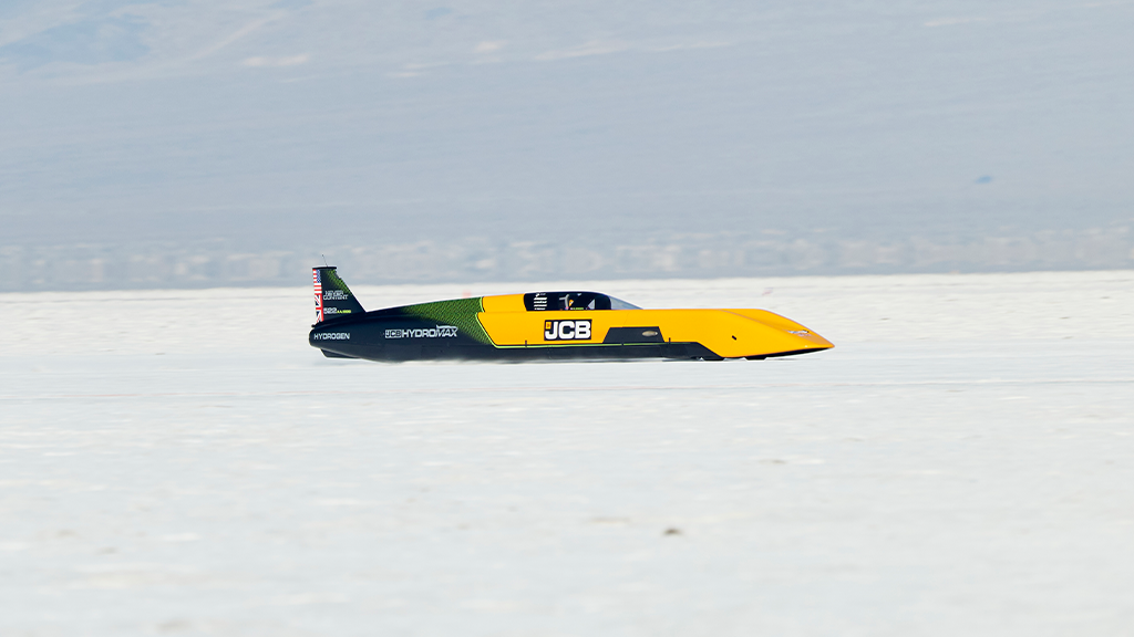 A needle-shaped yellow racing car on a white salt-flat desert A needle-shaped yellow racing car on a white salt-flat desert