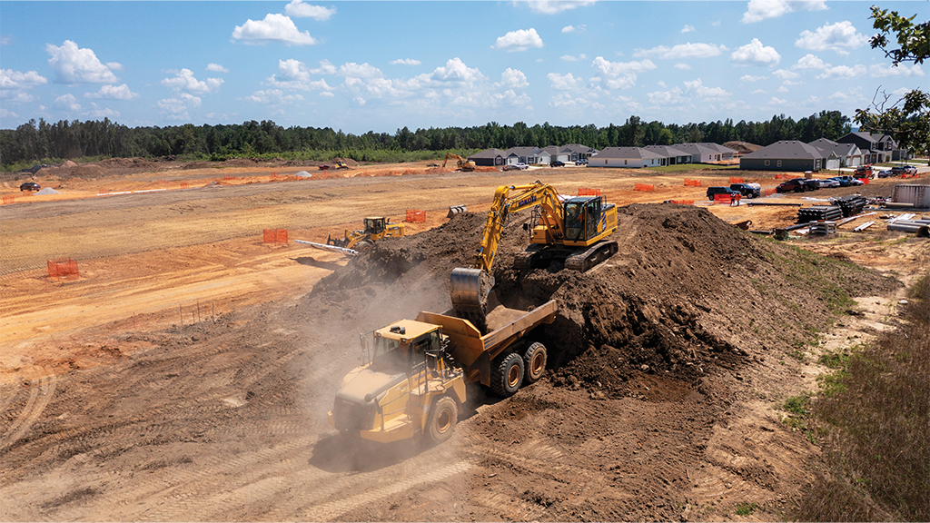 An active job site with an excavator, hauler, and other heavy machinery