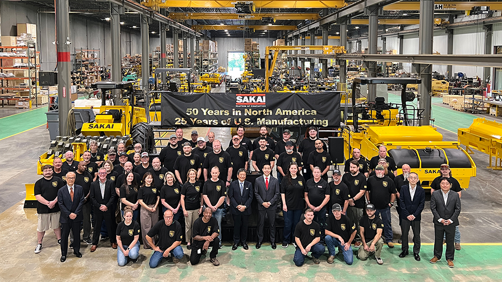 A photo of a large group of people inside of a manufacturing facility