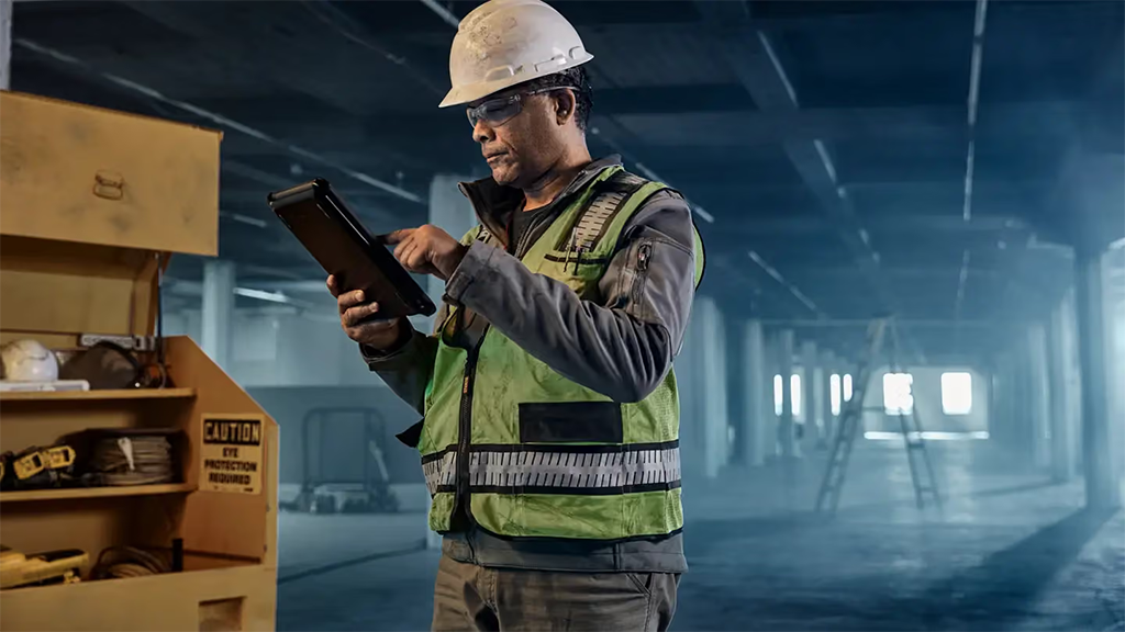 A man looks at a tablet while on a construction site A man looks at a tablet while on a construction site