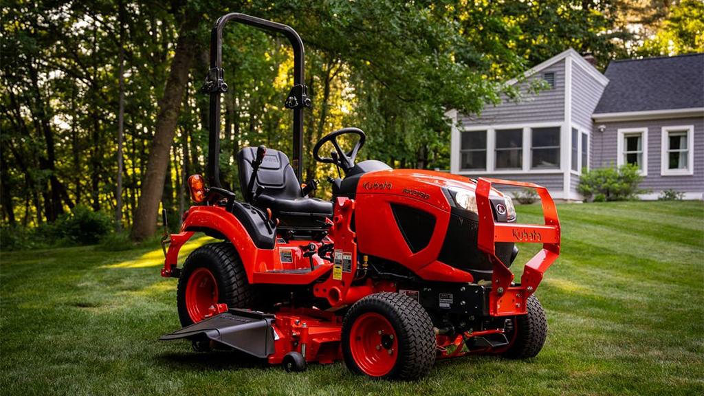 A red sub-compact tractor on a residential lawn