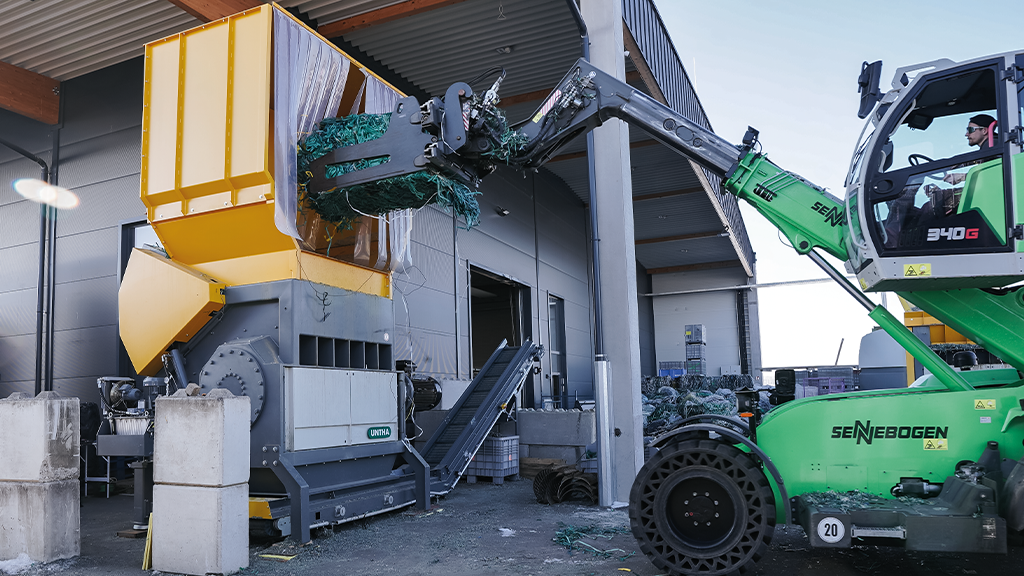 A material handler loads a bale of plastics into a shredder A material handler loads a bale of plastics into a shredder